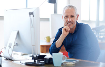 man at desk with hand on chin