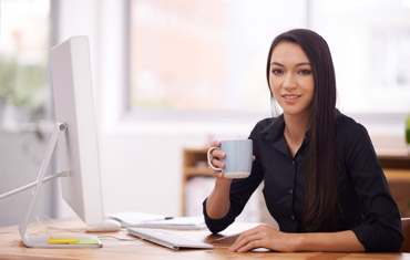 woman at desk holding mug